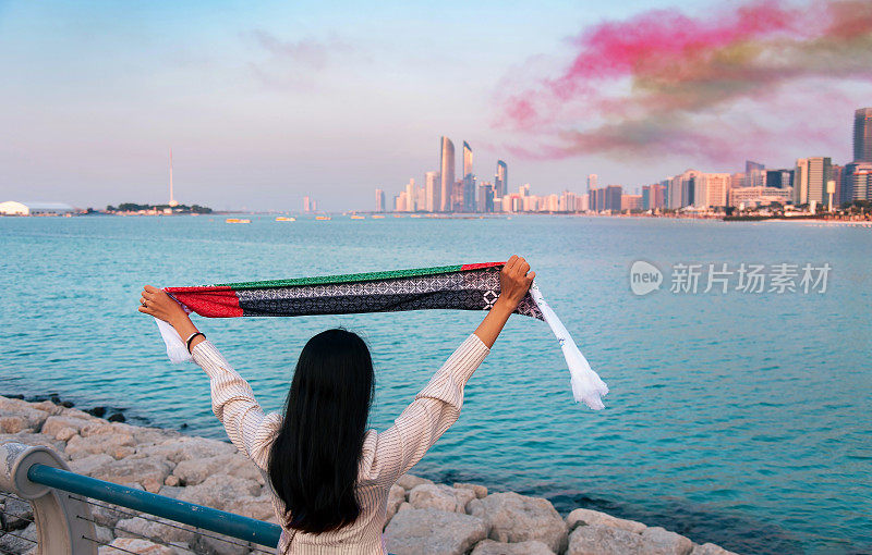 Female tourist holding UAE flag in Abu Dhabi celebrating national day holiday